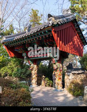 Busan, Corea del Sud - 14 febbraio 2026: Vista dell'ingresso del tempio Haedong Yonggungsa con architettura in legno tradizionale ornata, pilastri intagliati con draghi, Foto Stock