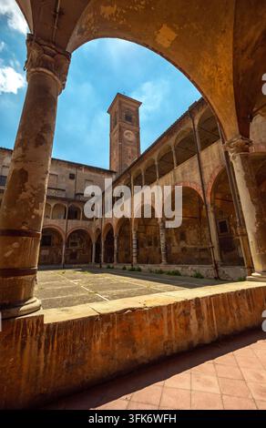 Bologna, Italia - 17 maggio 2018: Vista del chiostro storico con portici ad arco e un alto campanile sotto un cielo blu terso. Foto Stock
