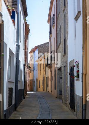 Strada stretta che si snoda attraverso una vecchia città con edifici colorati e mura in pietra Foto Stock
