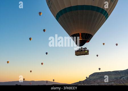 Cappadocia, Turchia – 06 agosto 2025: Un gruppo di persone si gode una passeggiata panoramica in mongolfiera mentre le fiamme del bruciatore si accendono, creando uno spettacolo spettacolare v Foto Stock