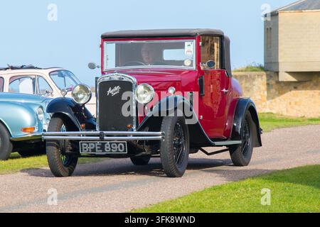 Coupé Austin Seven rosso che procede su un sentiero durante un evento di esposizione di veicoli al Tynemouth Priory and Castle Foto Stock
