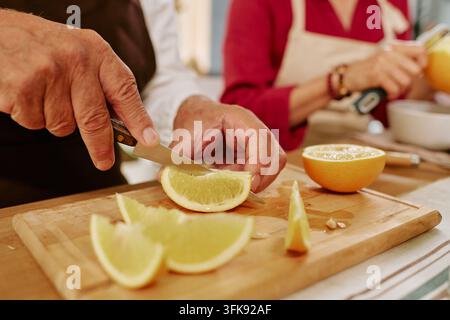 Coppia di anziani che prepara frutti di agrumi freschi e salutari in cucina Foto Stock