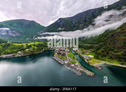 Vista aerea del villaggio di Flam incastonato nell'Aurlandsfjord, circondato da ripide montagne verdi, nuvole basse e acqua calma a Flam, Vestland, Norvegia Foto Stock