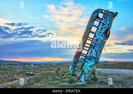 Un veicolo abbandonato si erge in verticale e dipinto con graffiti nella Foresta Internazionale delle Auto a Goldfield, Nevada. La luce dell'ora dorata e il la aspro Foto Stock
