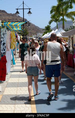 Mogan, Spagna - 23 settembre 2026: Visitatori passeggiano attraverso un vivace mercato di strada in una città resort tropicale costiera. Foto Stock