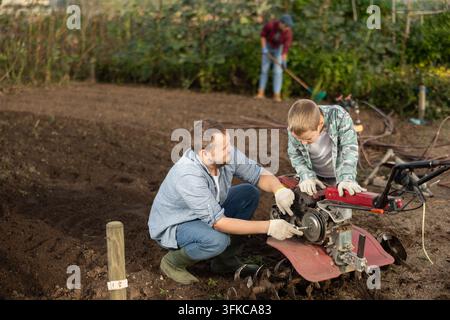 L'uomo e suo figlio stanno riparando attrezzature da giardino Foto Stock
