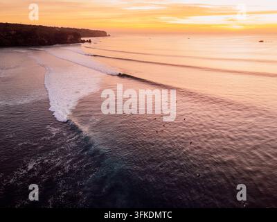 Vista aerea del tramonto su onde gentili che si infrangono su una costa tropicale Foto Stock
