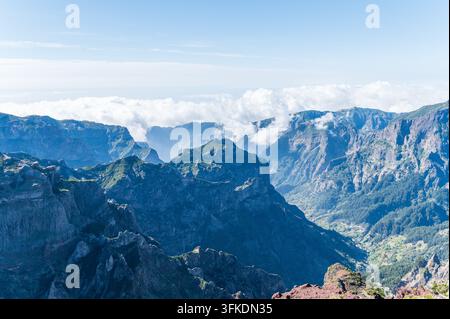 Panoramica mozzafiato su impervi picchi vulcanici e valli a Madeira, Portogallo, con un mare di nuvole bianche e soffici che riempiono la distanza Foto Stock