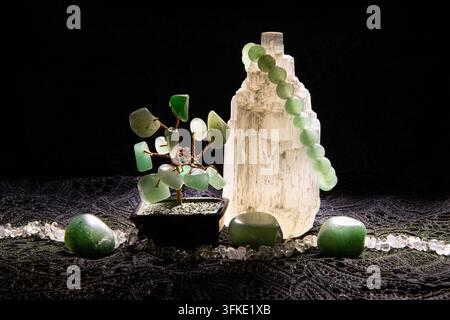 Le pietre di aventurina sono disposte attorno a un albero di cristallo di filo metallico, mentre un braccialetto fatto di perle di aventurina rotonde è posizionato su selinite per caricarlo. Foto Stock