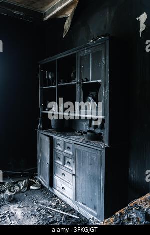 Armadio di legno bruciato in una stanza con pareti carbonizzate e detriti dopo un incendio. Disastro domestico, danni da incendio, rovina strutturale. Foto Stock