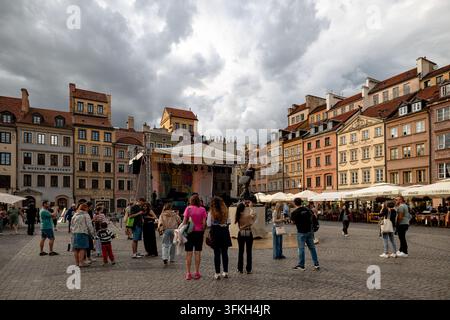 I visitatori si radunano intorno a un palco all'aperto nella piazza del mercato della vecchia città sotto nuvole drammatiche. Foto Stock