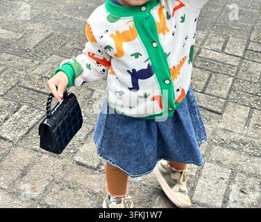 Accogliente cardigan per neonati con stampa colorata di dinosauri, bottoni davanti e bordi a costine verde brillante, che evidenzia la moda giocosa per bambini e k Foto Stock