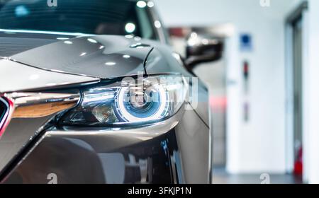Vista frontale di una nuova auto moderna argentata con fari a LED in uno showroom Foto Stock