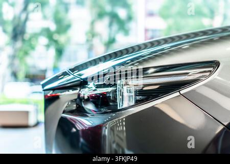 Vista frontale di una nuova auto moderna argentata con fari a LED in uno showroom Foto Stock