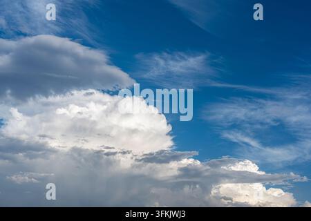 Nuvole cumulo imponenti e nuvole filiformi contro un cielo blu Foto Stock
