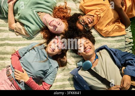 Ritratto di adolescenti felici e diversificati sdraiati su una coperta all'aperto Foto Stock