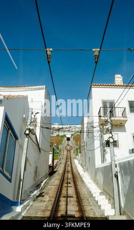 Binari del tram che si snodano tra edifici tradizionali a Nazare, Portogallo. Foto Stock