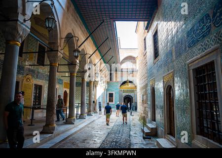 Istanbul, Turchia – 28 agosto 2026: Turisti che camminano attraverso il cortile storico del palazzo di Topkapi con piastrelle ornate e architettura tradizionale Foto Stock
