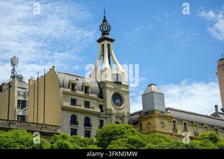 Edificio Art Nouveau ornato dell'inizio del XX secolo con una torre distintiva, una punta a globo e una rosona rotonda che si innalza sopra gli alberi verdi di Buenos Aires. Foto Stock