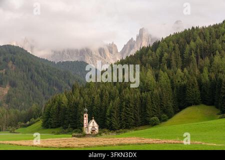 Chiesa di San Giovanni a Ranui con le Dolomiti di Odle e i prati verdi di Val di Funes, Alto Adige, Italia Foto Stock