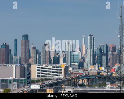 Veduta aerea che cattura il traffico lungo la rampa di accesso al ponte di Queensboro verso grattacieli moderni e torri residenziali sotto un cielo limpido s Foto Stock