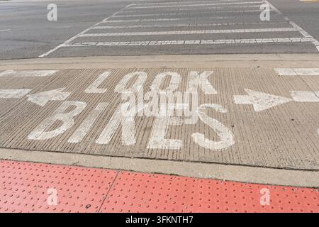 Avvertimento "Watch Bikes" dipinto sul marciapiede a un passaggio pedonale, concetto di sicurezza del ciclismo urbano e consapevolezza del traffico, foto orizzontale Foto Stock