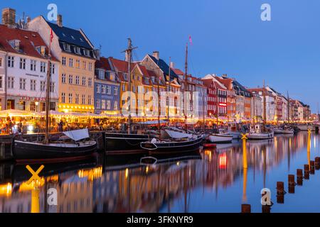 Barche davanti alle case dai tetti colorati di Nyhavn, ora blu, Copenaghen, Danimarca Foto Stock