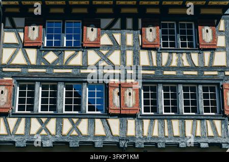 Vista dettagliata di un edificio tradizionale a graticcio con finestre disposte simmetricamente, intaglii di legno ornati e motivi decorativi nel legno Foto Stock
