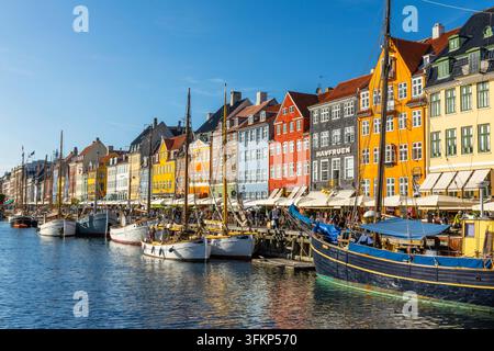 Barche davanti a case dai tetti colorati a Nyhavn, Copenaghen, Danimarca Foto Stock