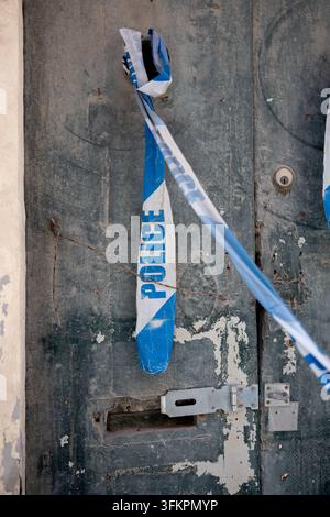 Nastro della polizia legato e appeso a una vecchia porta doppia in legno lasciando una scena del crimine concettuale misteriosa Foto Stock