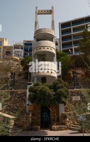 Una moderna scala in design di cemento a 3 piani che collega la strada bassa sul mare con le strade superiori a Bugibba, Malta. Foto Stock