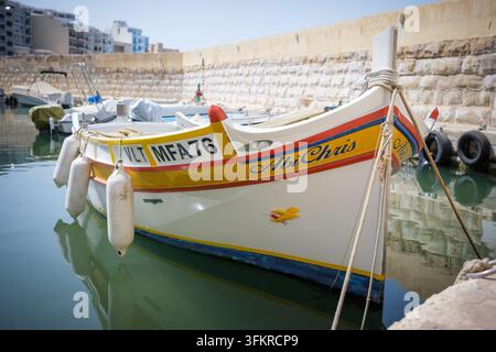 Tradizionali barche da pesca maltesi in legno colorate ormeggiate in un piccolo porto vicino a St Pauls Beach Bugibba, Malta Foto Stock