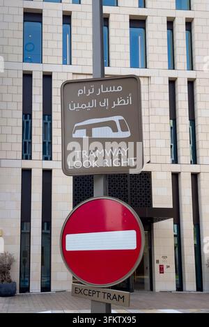 Segnale di avvertimento del tram in arabo e inglese montato sopra un segnale di divieto di ingresso a Msheireb Downtown Doha, Qatar. Foto Stock