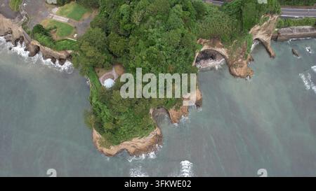 Vista aerea del promontorio di Inamuragasaki con vegetazione lussureggiante, scogliere rocciose e onde costiere a Kamakura, Kanagawa, Giappone. Foto Stock