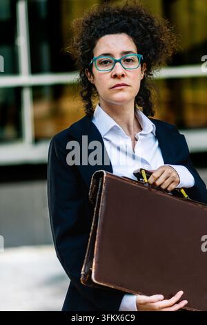 Donna d'affari sicura di sé con occhiali e una valigetta Foto Stock