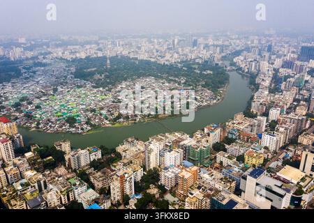 Vista aerea del paesaggio urbano denso che presenta un fiume tortuoso che separa i grattacieli da una zona residenziale densamente popolata a Dhaka, Dha Foto Stock