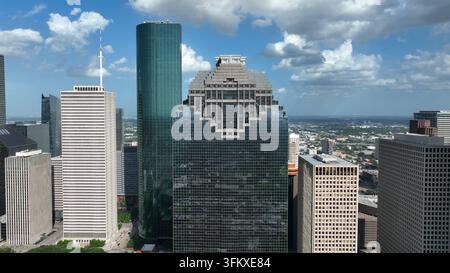 Vista aerea dello skyline di Houston con grattacieli moderni in vetro, edifici per uffici e architettura urbana sotto un cielo azzurro con nuvole sparse Foto Stock