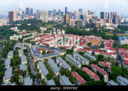 Vista aerea del mercato di Tiong Bahru circondato da edifici residenziali storici a più piano con tetti rossi e vegetazione lussureggiante, con lo skyline della città di Singapore Foto Stock
