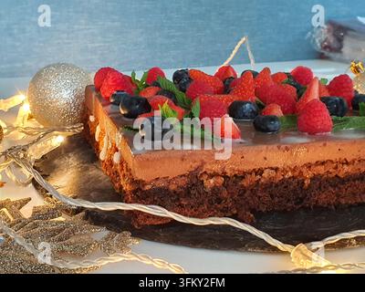 Un dessert al cioccolato a strati rettangolare, probabilmente una torta o una crostata a base di brownie, posizionato su una tavola da portata in ardesia scura. Il dessert presenta una consistenza densa, Foto Stock