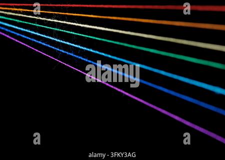fili di cucito multicolori a forma di arcobaleno su sfondo nero in primo piano Foto Stock