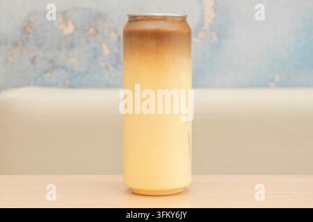 Caffè freddo e latte a strati in un bicchiere alto davanti a un muro blu consumato Foto Stock