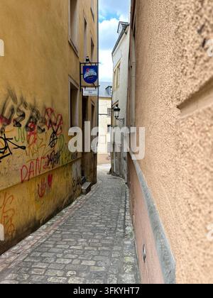 Stretta via storica con graffiti e ciottoli. Una stretta via storica europea tortuosa con ciottoli, colorata Foto Stock
