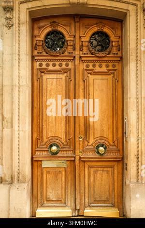 Elegante porta in legno con intagli dettagliati, griglie in ferro battuto, pomelli in ottone e una tradizionale fessura postale a Parigi Foto Stock