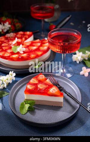 Deliziosa torta alla gelatina di fragole a strati con guarnizione di frutta fresca e menta, servita insieme a rinfrescanti bevande rosse, perfetta per una celebrazione o Foto Stock
