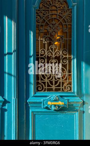 Porta blu ornata a Parigi con intricate griglie in ferro battuto e dettagli architettonici classici, ingresso vintage Foto Stock