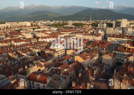 Vista aerea della storica città di Grenoble con caratteristici tetti dalle tegole rosse, architettura urbana e la catena montuosa delle Alpi circostante in Foto Stock