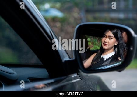 Riflesso di una donna malese nello specchietto laterale dell'auto Foto Stock