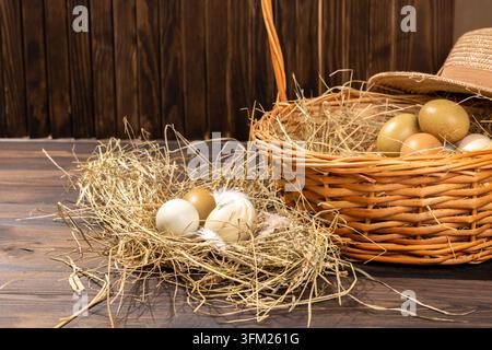 Uova di pollo biologiche fresche che mostrano colori e texture naturali, appoggiate in un nido di fieno e un cesto intrecciato su una superficie di legno scuro, simboleggiando la fattoria Foto Stock