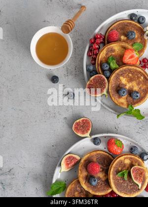 Disposizione per la colazione a soffitto con pancake ricoperti di bacche fresche, fichi e miele Foto Stock