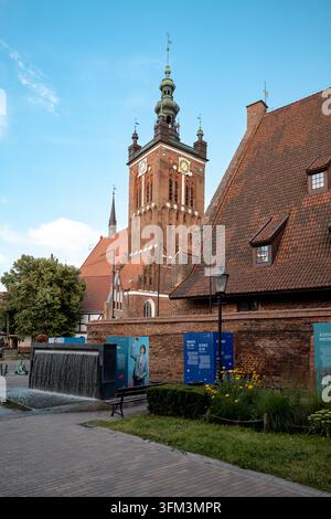 La chiesa di Santa Caterina si erge sopra gli edifici storici in mattoni del centro di Danzica. Foto Stock